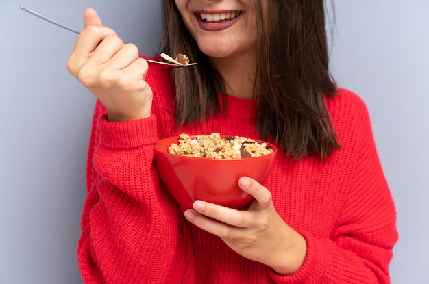 Young woman sitting on the floor and holding a bowl of cereals