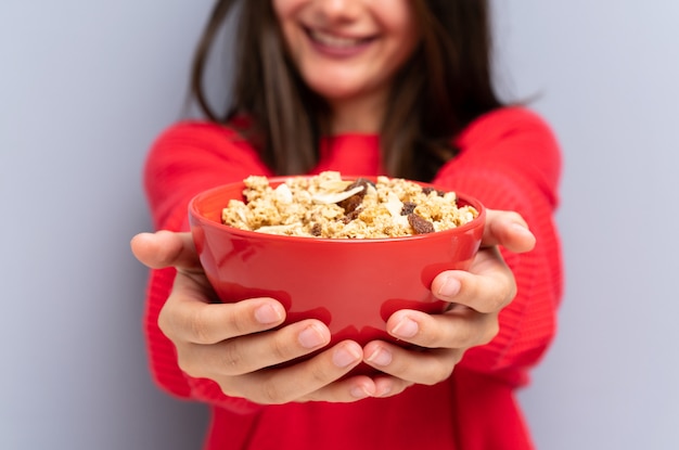 Photo young woman sitting on the floor and holding a bowl of cereals