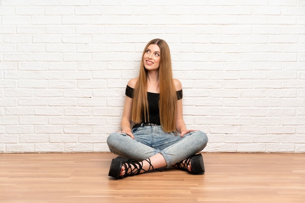 Photo young woman sitting on the floor laughing and looking up