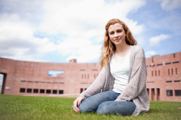 Young woman sitting on a lawn outside a college