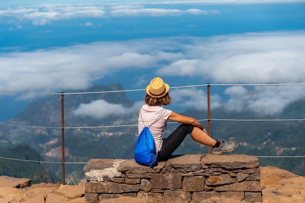 A young woman sitting at the Miradouro do Juncal on Pico do Arieiro Madeira Portugal