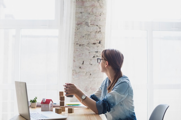 Young woman sitting in office holding coffee cup in hand