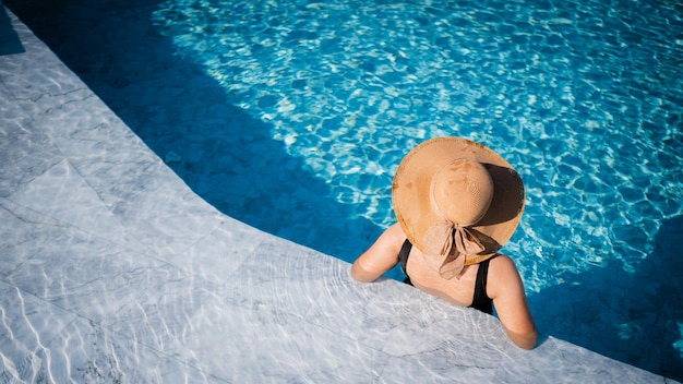 Young woman sitting in the pool in luxury resort