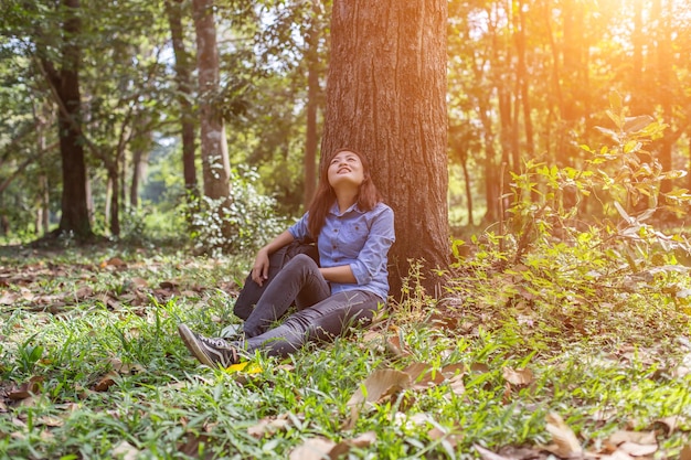 Photo young woman sitting on tree trunk in forest