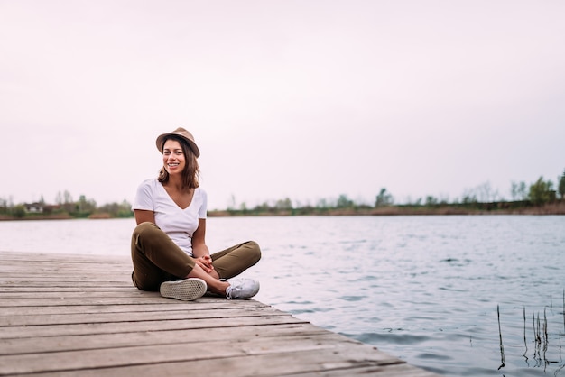 Young woman sitting on wooden pier, relaxing.