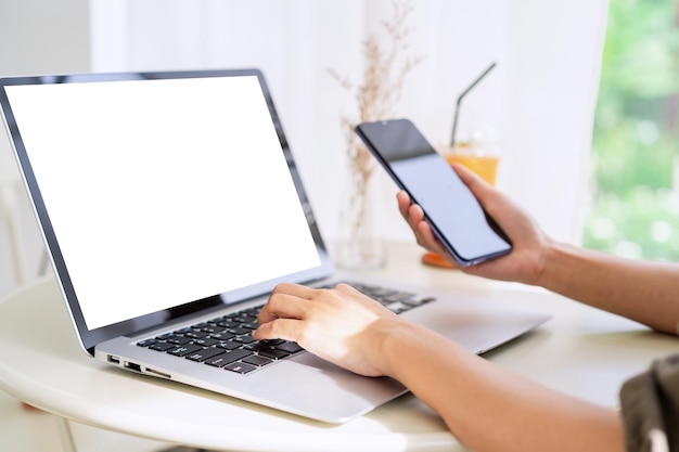 Young woman sitting and working on laptop and smart phone at coffee shop