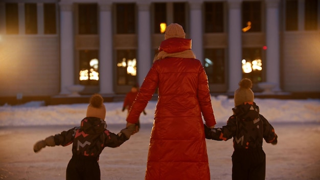 A young woman skating on public ice rink with her kids