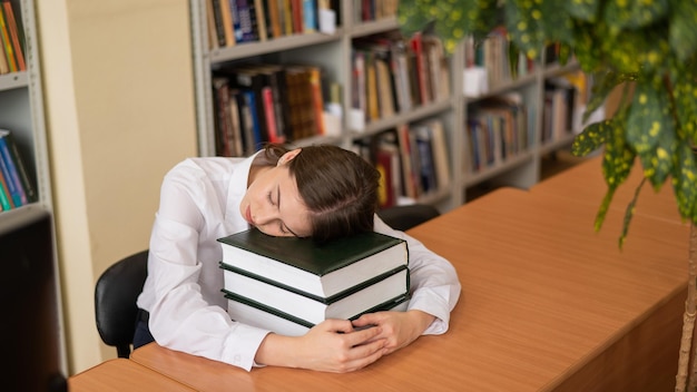 Young woman sleeping on textbooks in a public library