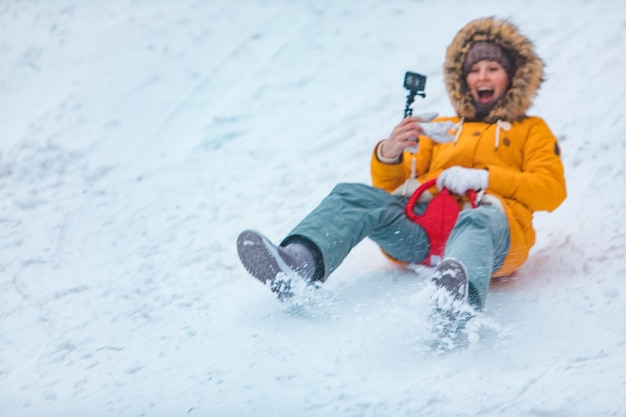 Young woman sliding down by snowed hill