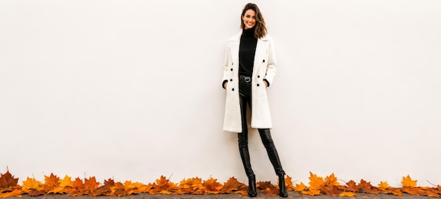 Photo young woman slim trendy autumn attire poses with style neutral backdrop orange leaves ground seasonal elegance captured