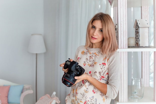 A young woman smiles with a camera in her hands