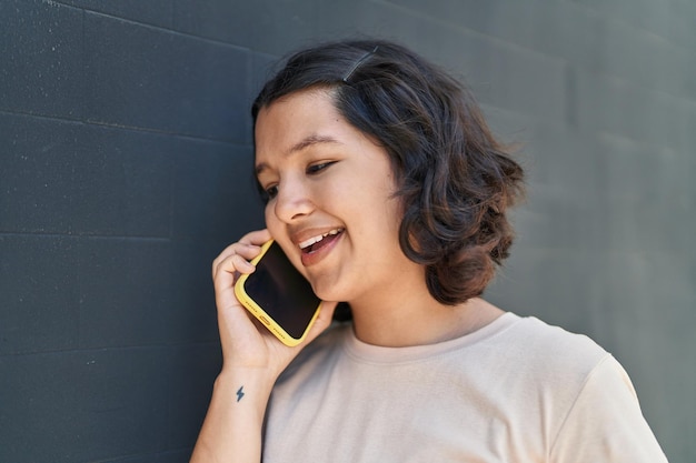 Young woman smiling confident talking on the smartphone at street