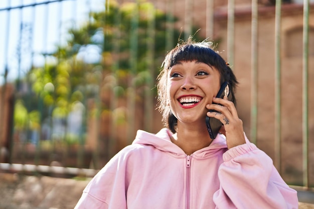 Young woman smiling confident talking on the smartphone at street