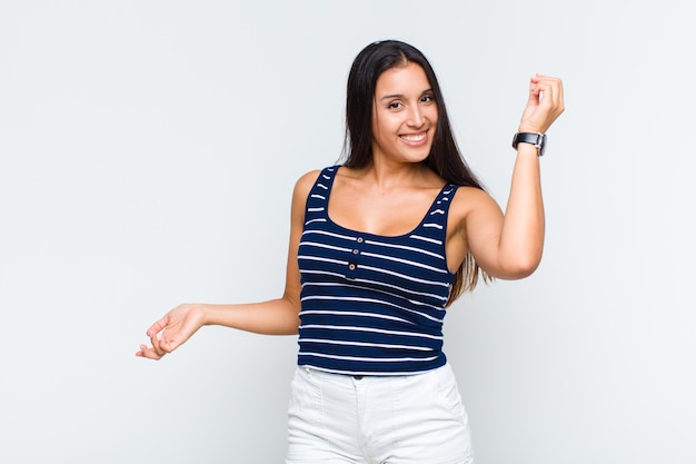 Young woman smiling, feeling carefree, relaxed and happy, dancing and listening to music, having fun at a party