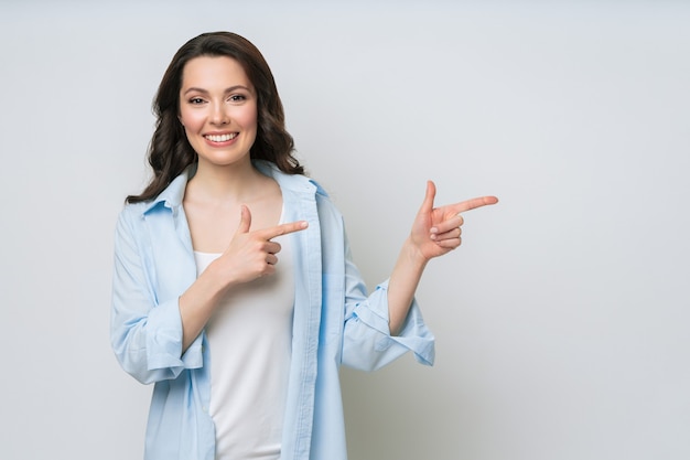 Young woman smiling and gesturing to copy space