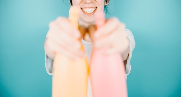 Young woman smiling happily to camera while aiming to camera a pair of water sprayer to refresh during summer Holidays outdoors with copy spaceColor background image