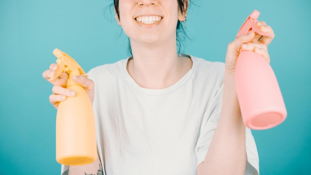 Young woman smiling happily to camera while holding a pair of water sprayer to refresh during summer Color background image