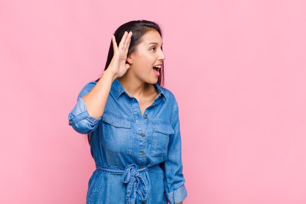 Young woman smiling, looking curiously to the side, trying to listen to gossip or overhearing a secret