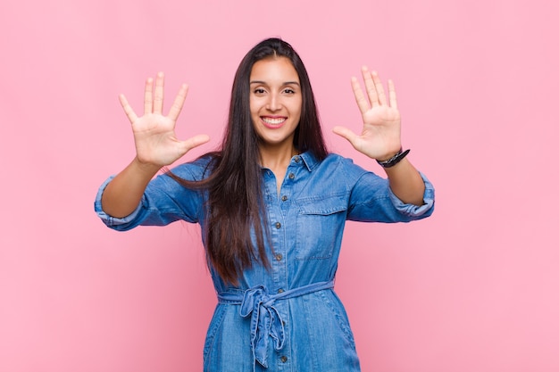 Young woman smiling and looking friendly, showing number ten or tenth with hand forward, counting down