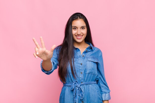 Young woman smiling and looking friendly, showing number two or second with hand forward, counting down