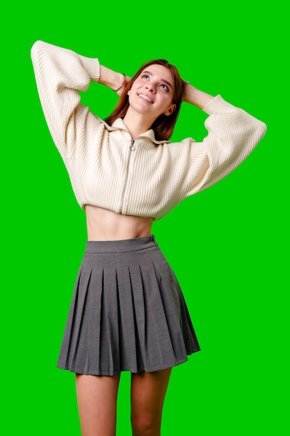 Young woman smiling and looking upward while holding her hair on a green background