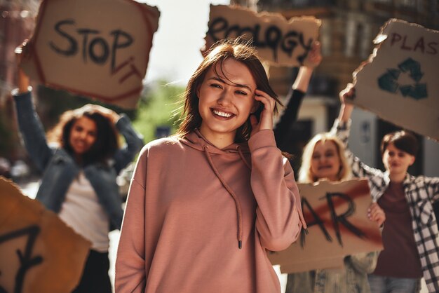 Young woman smiling while protesting for ecology with group of female activists on the road 