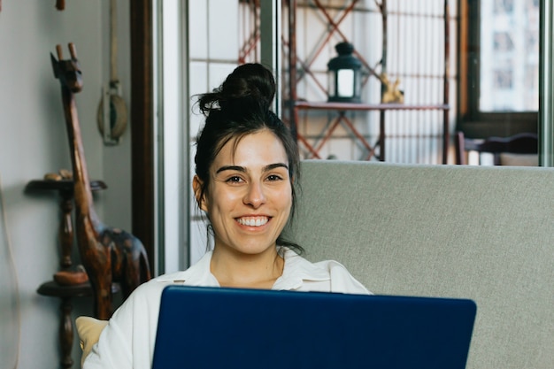 Young woman smiling while working from home with the laptop