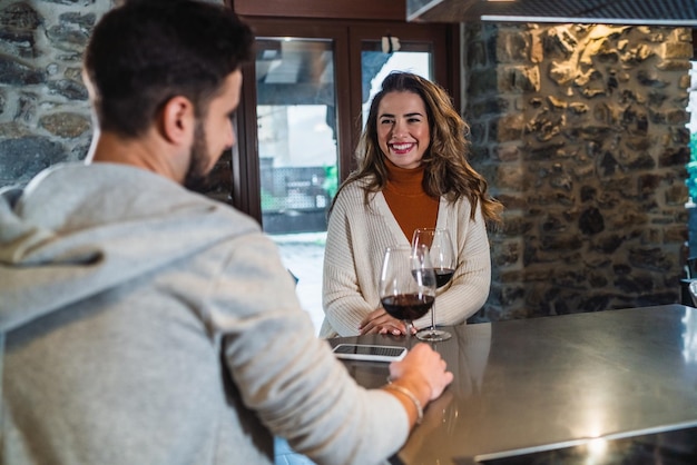 A young woman smiling with the couple with a glass of red wine in the kitchen of their home