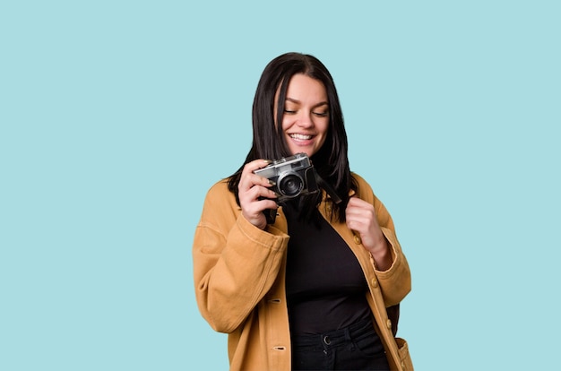 Young woman smiling with film camera looking through viewfinder excited by new passion