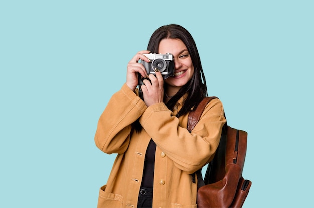 Young woman smiling with film camera looking through viewfinder excited by new passion