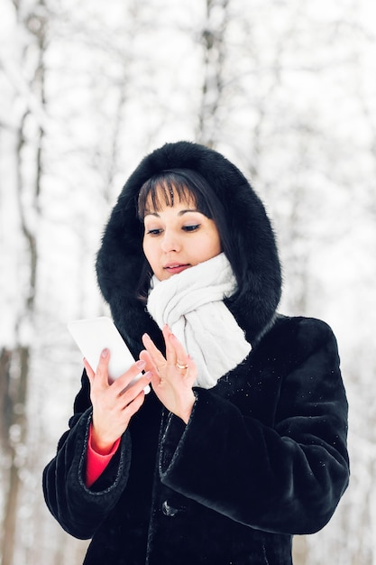 Young woman smiling with smart phone and winter landscape.