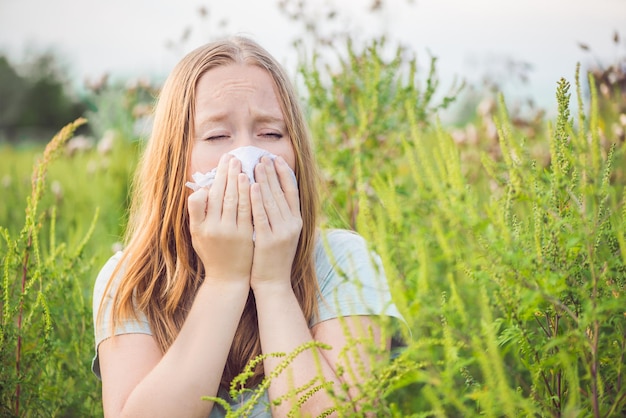 Young woman sneezes because of an allergy to ragweed