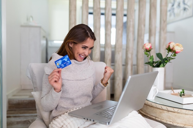 Young Woman On Sofa Shopping Online With Debit Card. Beautiful girl using laptop computer for online shopping at home. Beautiful girl using laptop computer for online shopping at home