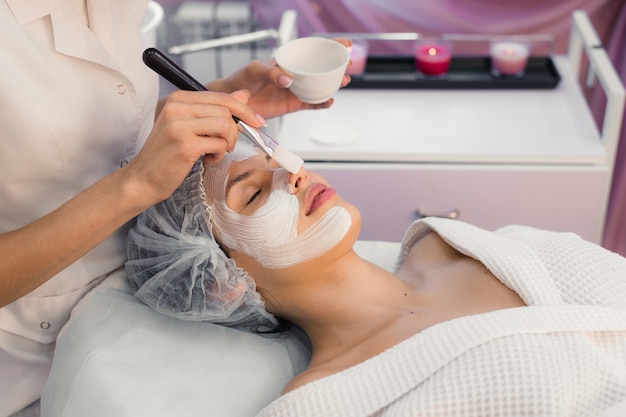 Young woman at spa procedures applying mask