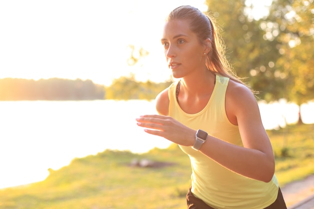 Young woman in sports clothing running while exercising outdoors.