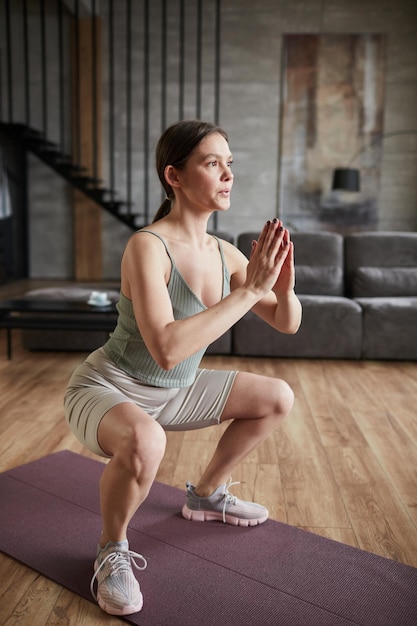 Young woman in sports clothing training her body during sports training in the morning