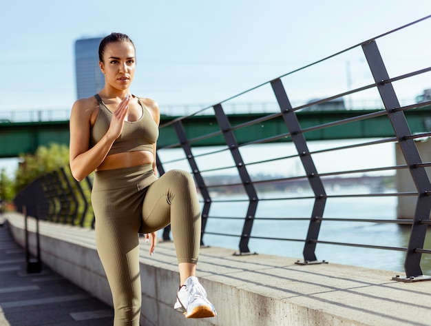 Young woman in sportswear stretching on a river promenade