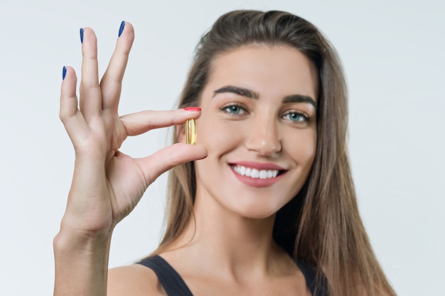 Young woman in sportswear with vitamin D, E, A