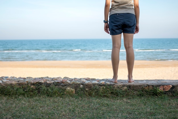 Young woman standing alone and looking at the sea.