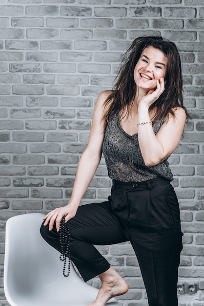 Young woman standing by the chair looking at the camera and smiling, beauty