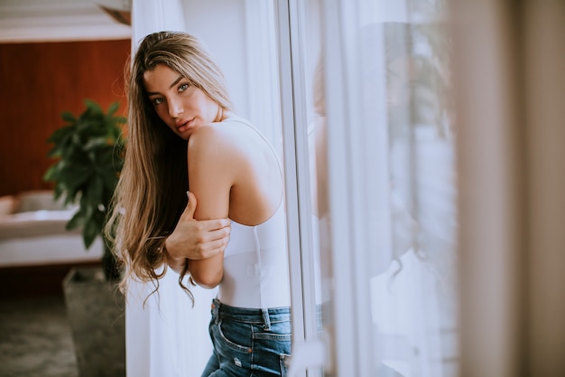 Young woman standing by the window in the room