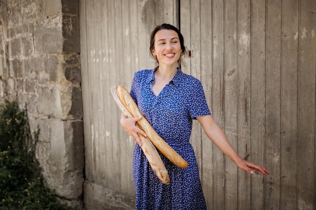 Young woman standing with french baguettes in the countryside