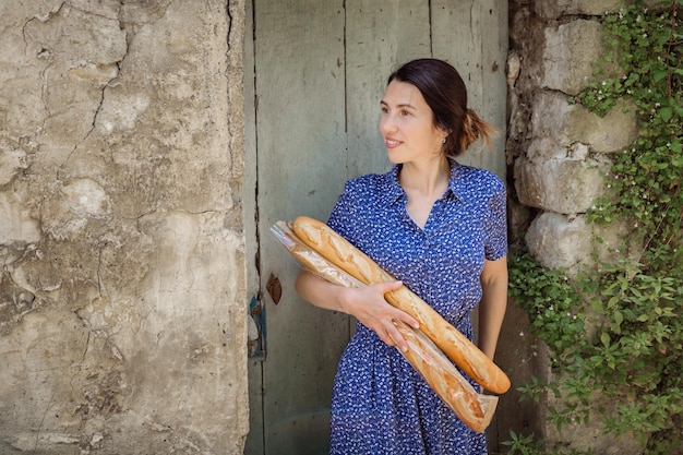 Young woman standing with french baguettes in the countryside