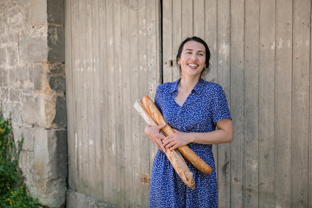 Young woman standing with french baguettes in the countryside