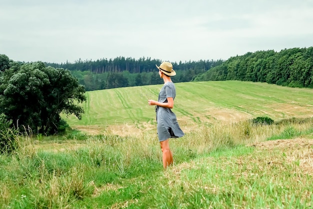 a young woman stands against the background of mowed wheat fields. agro industry concept