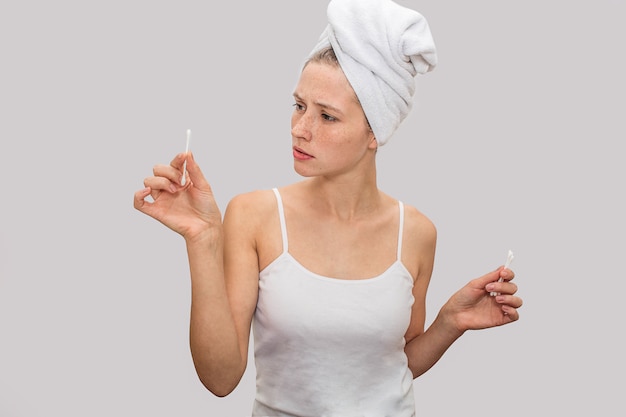 Young woman stands and holds ear sticks in hands.