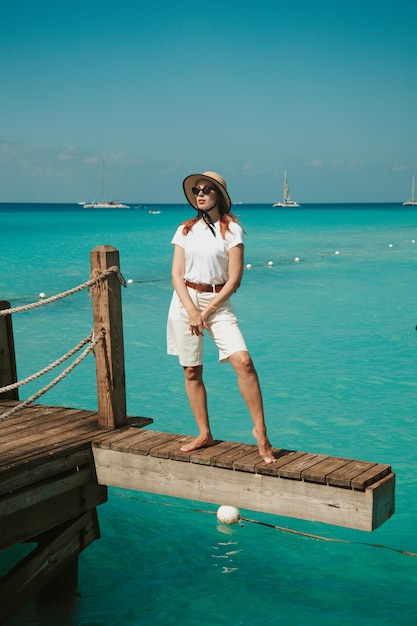 Young woman stands on the pier and looks into the distance