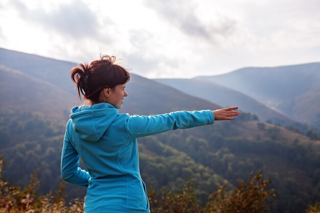 Young woman stands at the top and looking at the mountains. 