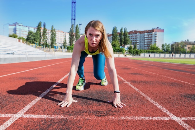 A young woman in the starting position for running on a sports track Sportswoman at the start