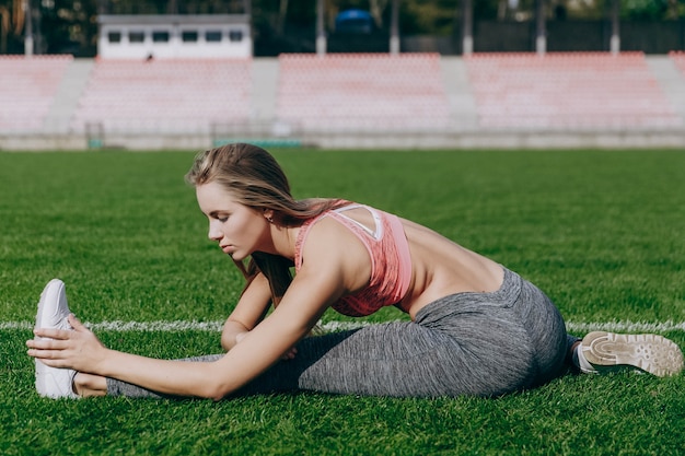 Young woman stretches on the stadium before a workout 